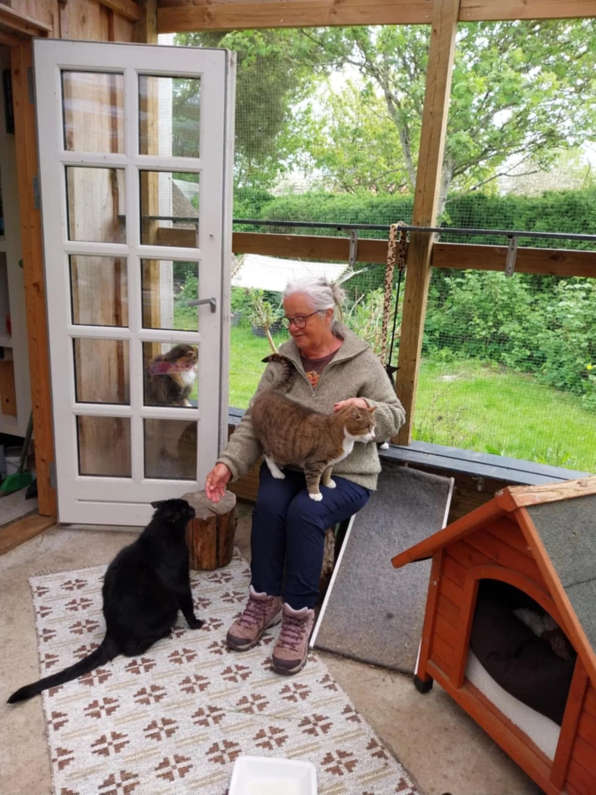 Karin sidder på veranda og hygger med katte - en frivillig hjælper i aktion